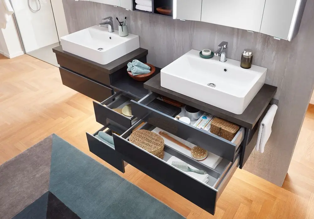 Modernes Badezimmer mit zwei Waschbecken und offenen Schubladen, in denen sich Stauraum befindet