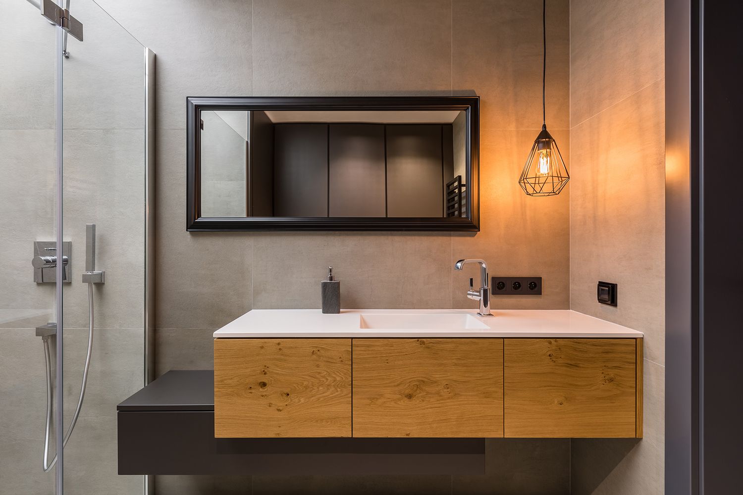 Badezimmer mit Holzschränken, weißem Waschbecken, Spiegel und geometrischer Pendelleuchte