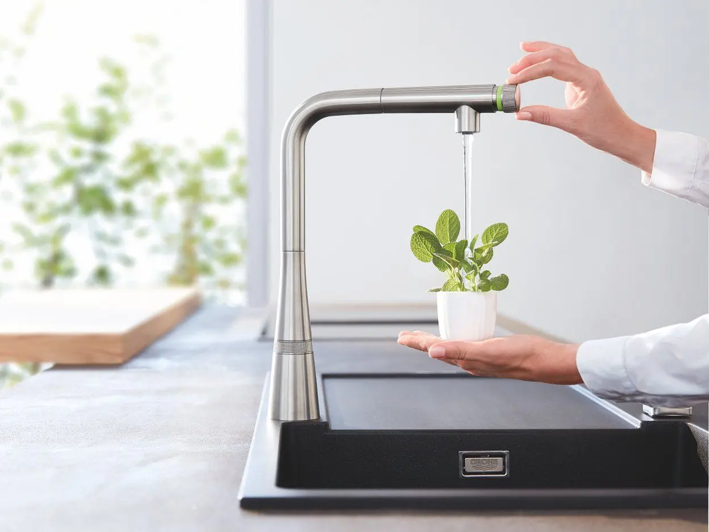 Kleine Pflanze wird unter einem Wasserhahn gegossen