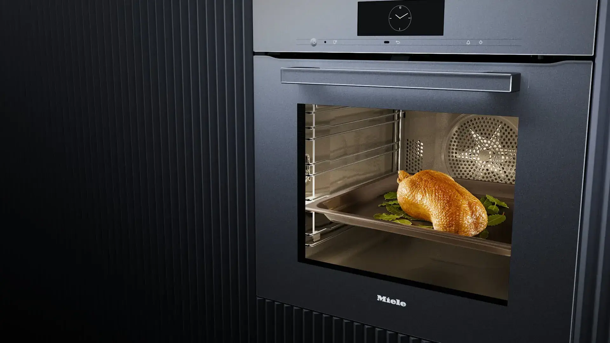 Dunkler moderner Ofen indem ein Huhn gebacken wird