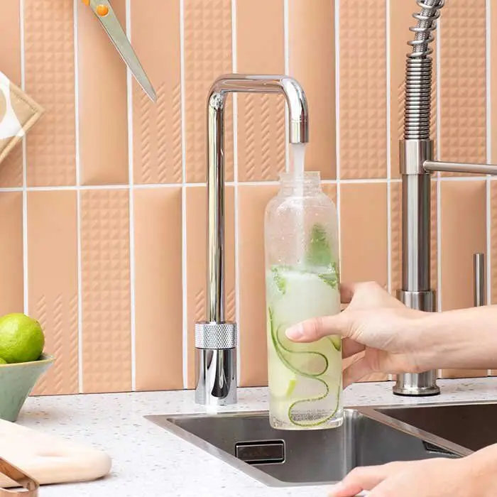 Hochmoderner Wasserhahn füllt eine Flasche mit Gurke auf