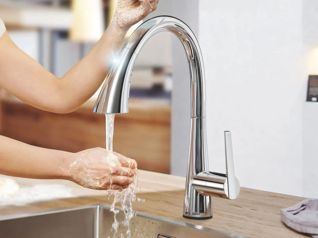 Person wäscht sich unter einem silbernen Wasserhahn die Hände